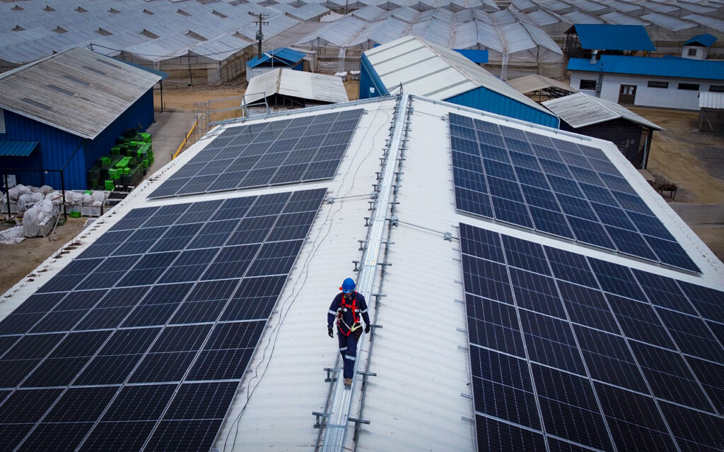 Trabajador de INNSOLAR CHILE portando equipo de seguridad sobre un techo con paneles solares.